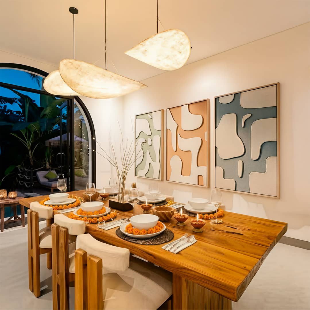 Set of three abstract framed panels above a Diwali dinner table laid with marigolds and diyas