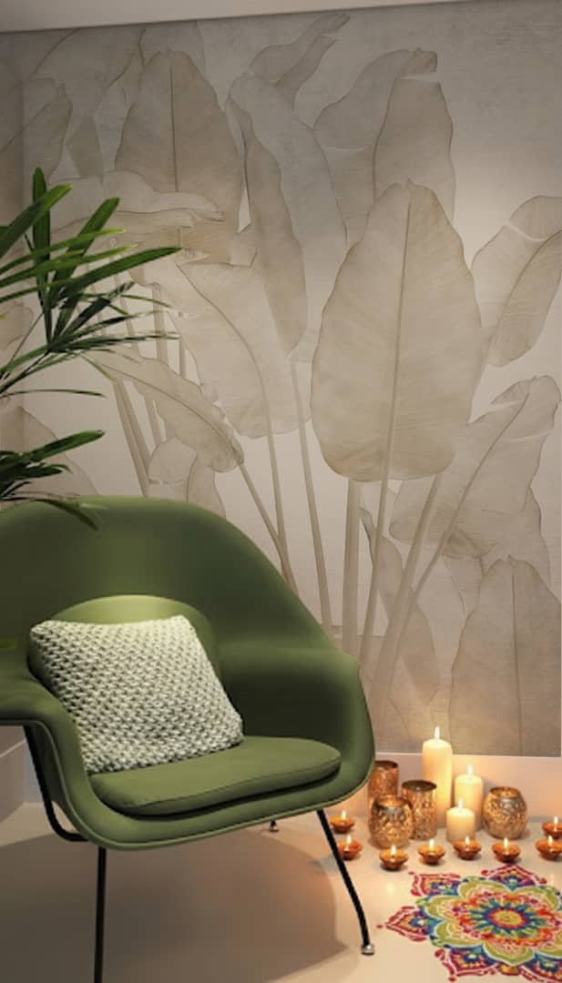 Soft banana-leaf botanical wallpaper behind a green armchair, with candles, diyas and a small rangoli for Diwali